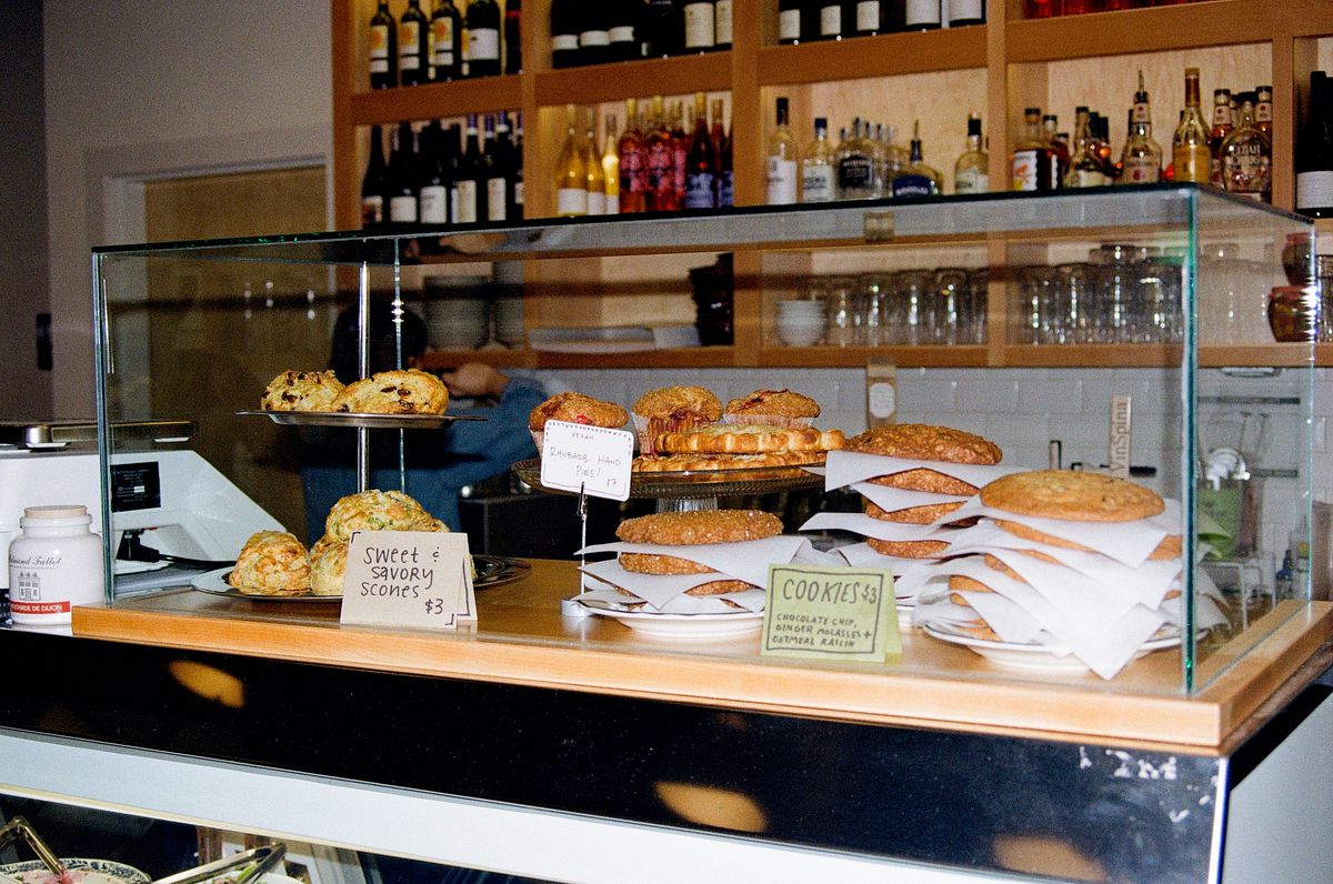 Cookies, scones, and biscuits sit on a wooden counter in a glass case at Taylor Street Kitchen.