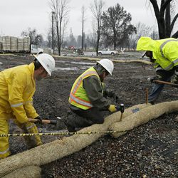 Workers secure rolls of wattle around a homesite for erosion control in the wildfire damaged Coffey Park neighborhood, Monday, Jan. 8, 2018, in Santa Rosa, Calif. Storms brought rain to California on Monday and increased the risk of mudslides in fire-ravaged communities in devastated northern wine country and authorities to order evacuations farther south for towns below hillsides burned by the state's largest-ever wildfire. (AP Photo/Eric Risberg)