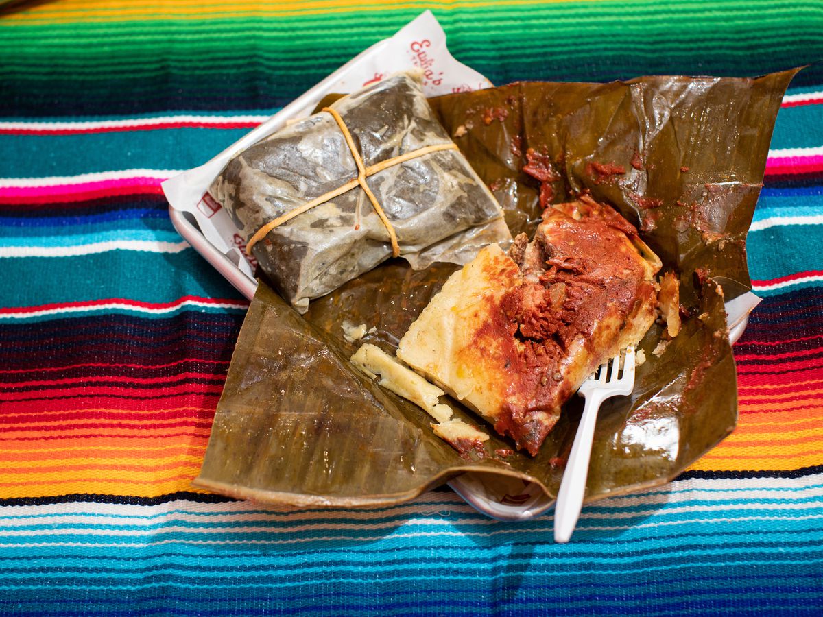 A Oaxaqueño tamal overflows with pork ribs against a colorful background.