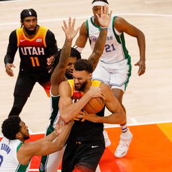 Utah Jazz center Rudy Gobert, center, keeps the possession as Dallas Mavericks center Moses Brown, left, attempts to intercept during an NBA game at Vivint Arena in Salt Lake City on Saturday, Dec. 25, 2021.