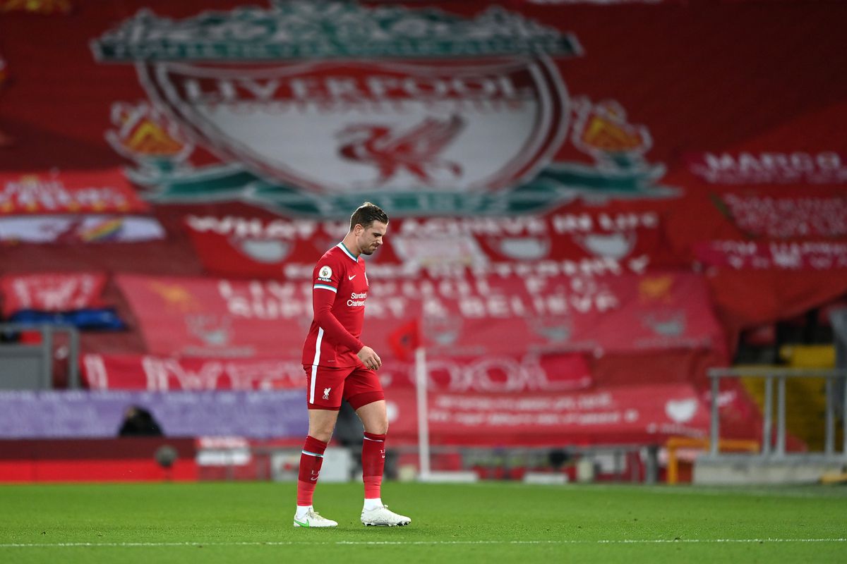 Jordan Henderson of Liverpool leaves the pitch as he is substituted off due to injury during the Premier League match between Liverpool and Everton at Anfield on February 20, 2021. Behind the captain is a banner-laden Kop.