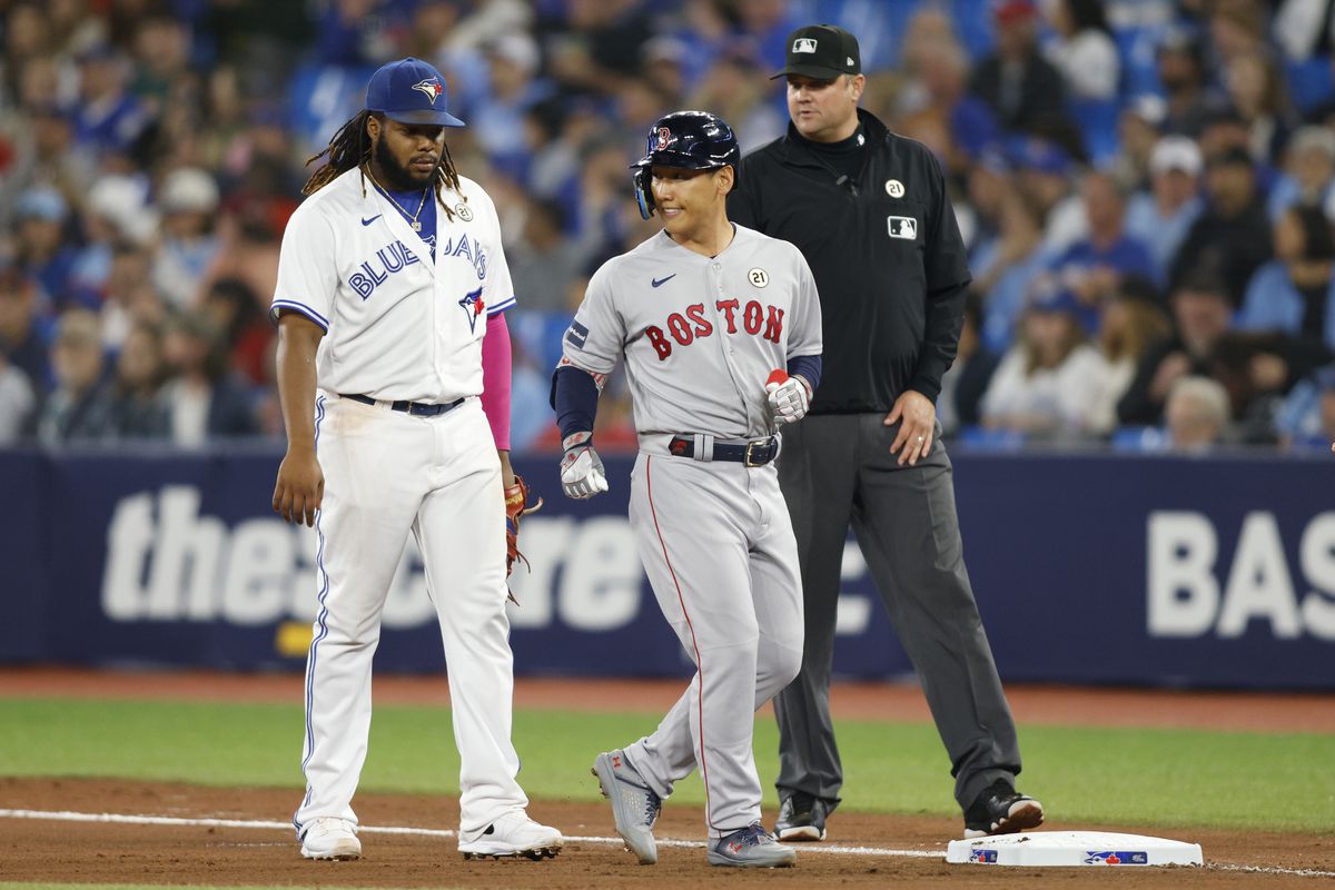 Masataka Yoshida of the Boston Red Sox smiles as he takes first base next to Vladimir Guerrero Jr. of the Toronto Blue Jays after a single in the seventh inning against the Toronto Blue Jays at Rogers Centre on September 15, 2023 in Toronto, Canada.