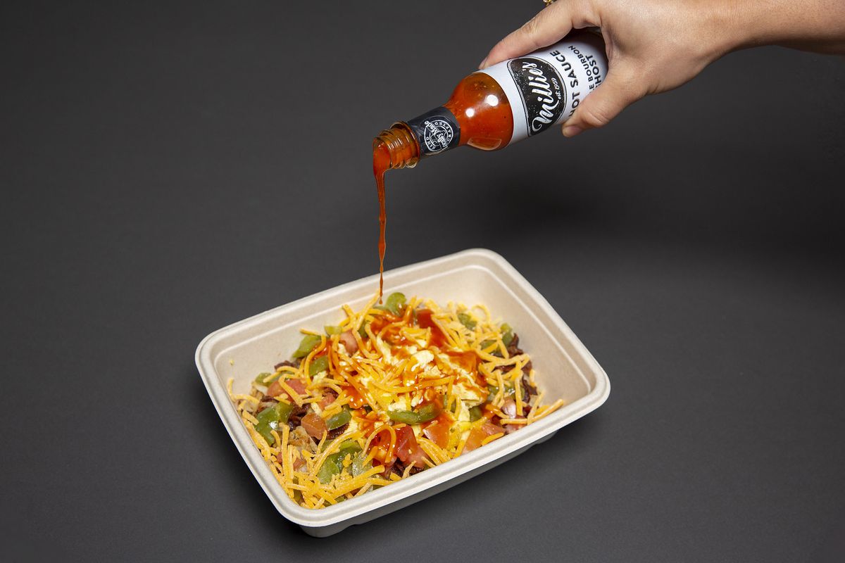 Hot sauce pouring down on a cheesy taco salad.
