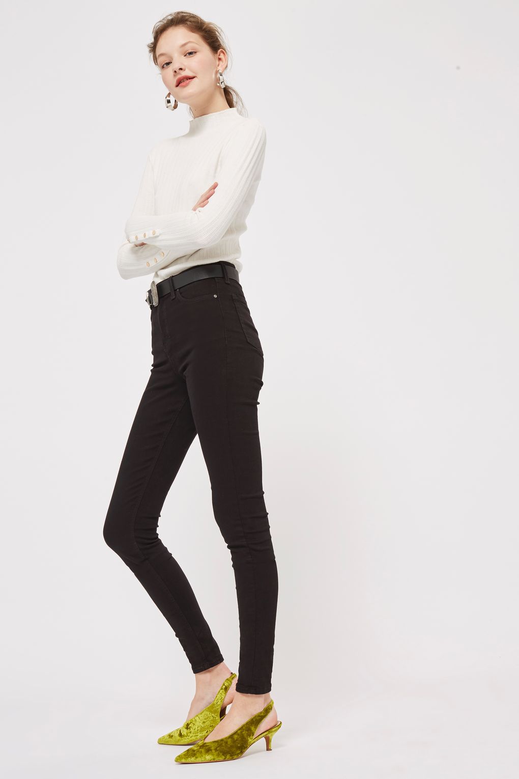 A model wearing black skinny jeans and a white turtleneck