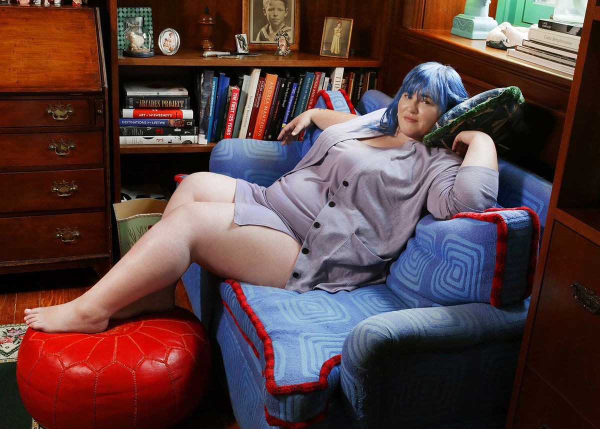 A model wearing periwinkle loungewear sitting on a couch