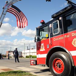 A flag is flown in between the ladders of two fire trucks to honor Juan Bucio. | Victor Hilitski/For the Sun-Times
