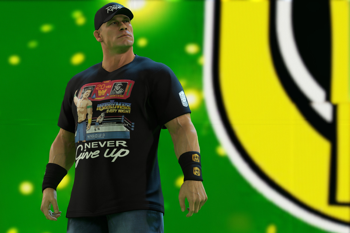WWE superstar John Cena making his entrance in WWE 2K23; he is wearing a t-shirt that shows him wrestling in 8-bit video game art, over the motto “Never Give Up.”