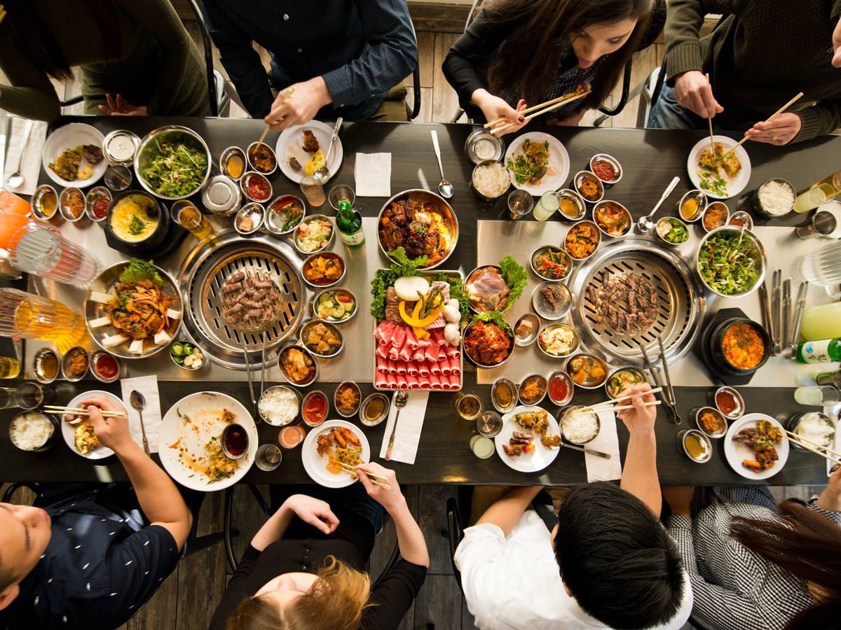 Customers sit at a table surrounded by a huge spread of Korean barbecue.