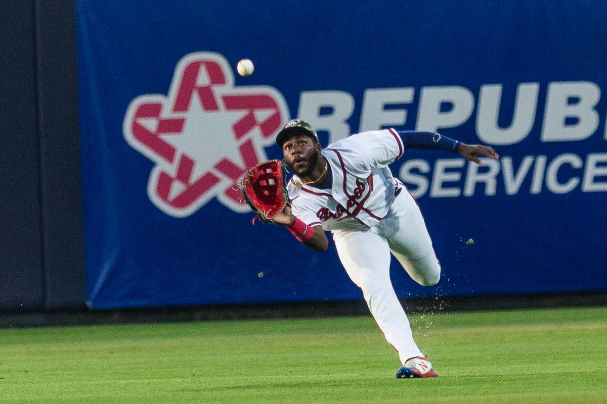 Michael Harris is about to make a running catch in a night game for the Rome Braves. His eyes are locked on the ball in the air just a foot in front of him, and he is bent over at the waist attempting to make the play.