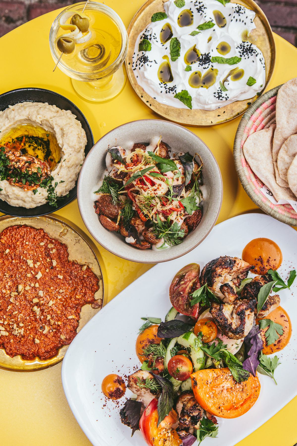 Several dishes with Middle Eastern fare, like hummus, fresh pita, spiced and roasted vegetables, and more.