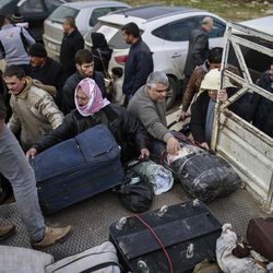 Syrians put their belongings into vehicles after crossing into Turkey at the Cilvegozu border gate with Syria, near Hatay, southeastern Turkey, Sunday, Dec. 18, 2016. Several people were able to cross into Turkey after they managed to leave the embattled Syrian city. The Aleppo evacuation was suspended Friday after a report of shooting at a crossing point into the enclave by both sides of the conflict. 