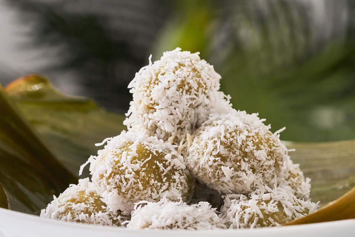 A stacked pyramid of green rice balls covered in coconut flakes.