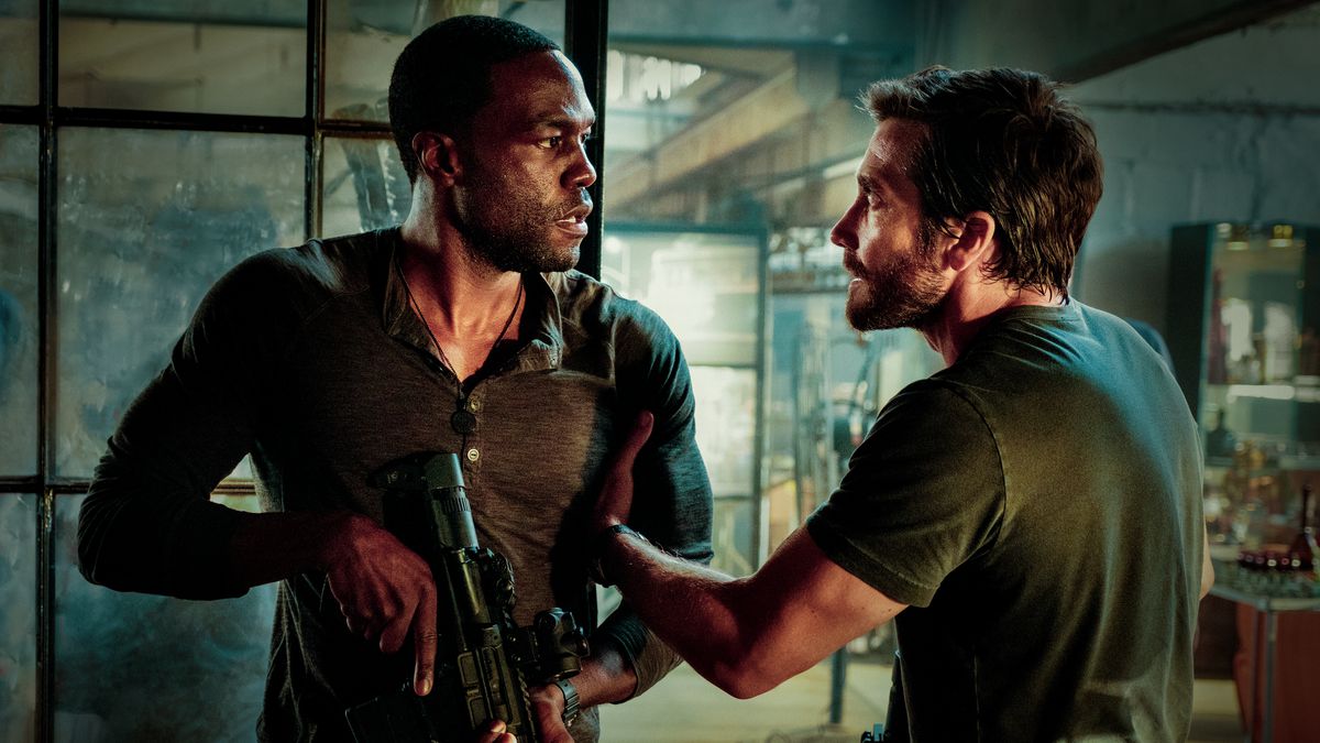 Jake Gyllenhaal and Yahya Abdul-Mateen II face off, holding automatic weapons, in Ambulance