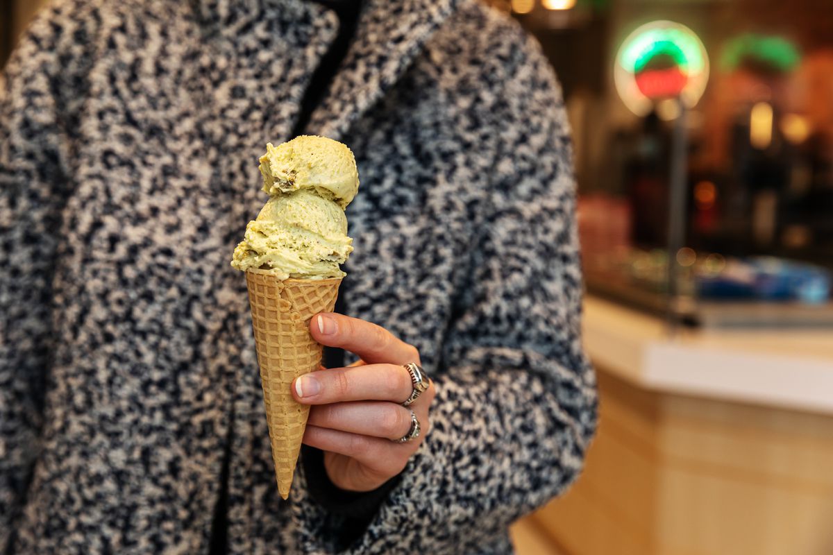 A woman wearing rings holding a waffle cone of gelato at Momento Gelato in Corktown.