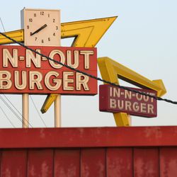 In-N-Out Burger signs, one the foreground from the fast food chain's original location, and one in the background at its new location across the Interestate 10 freeway, are seen on Tuesday, June 8, 2010, in Baldwin Park, Calif. (AP Photo/Adam Lau)