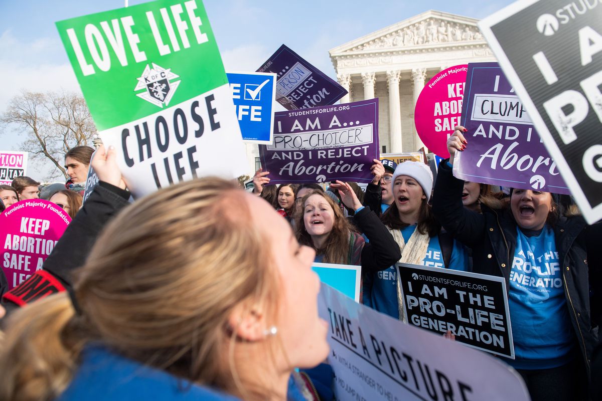 Anti-abortion activists, including one holding a sign reading “Love life, choose life,” as well as abortion-rights activists, demonstrate at the March for Life outside the US Supreme Court in Washington, DC, on January 18, 2019.