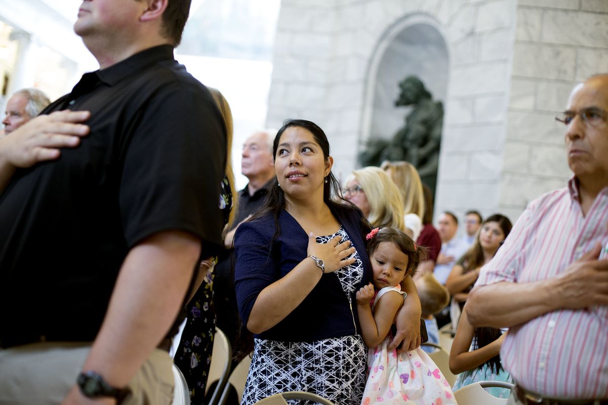 Martha Madariaga Borden and her daughter, Ariana, stand during the national anthem during a naturalization ceremony for approximately 125 people from more than 40 countries at the state Capitol in Salt Lake City on Wednesday, July 19, 2017. Borden's husba