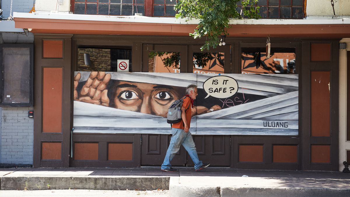 A man walking in front of a temporarily shuttered bar on East Sixth Street back in early May 2020