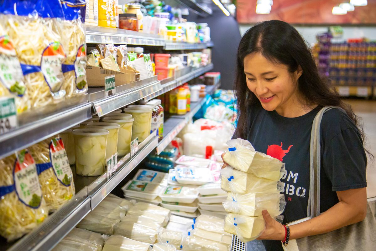 Heirloom Market BBQ chef Jiyeon Lee picks up four plastic wrapped packages of Buford Highway Farmers Market homemade tofu