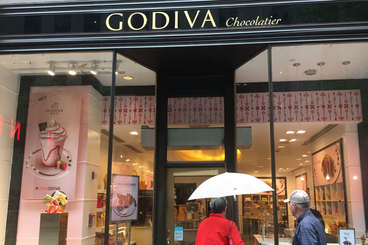 Exterior of a Godiva chocolate store, with two people standing in front of it.