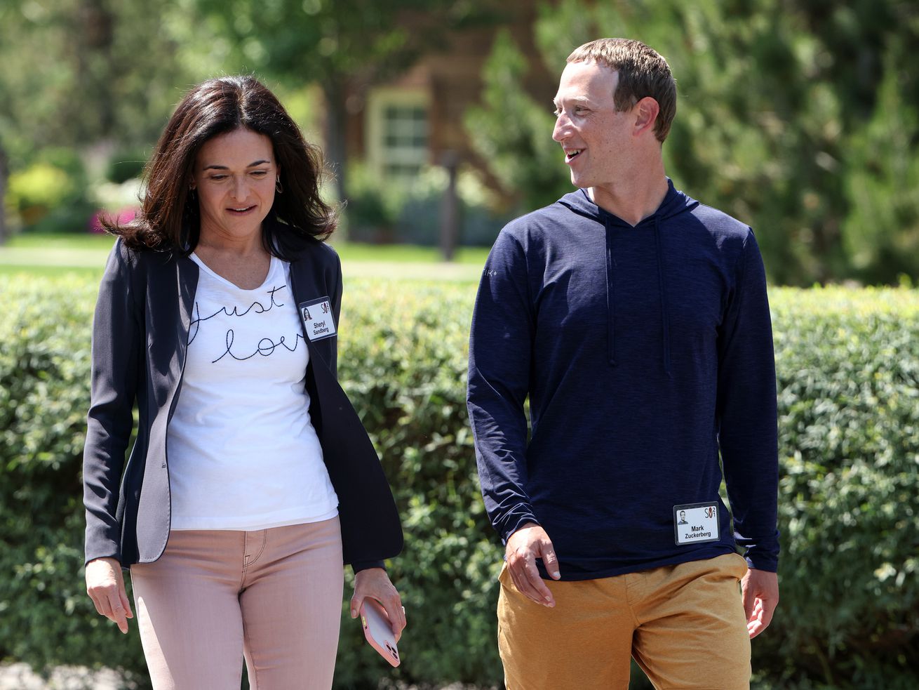 Sheryl Sandberg and Mark Zuckerberg walking side by side outdoors.