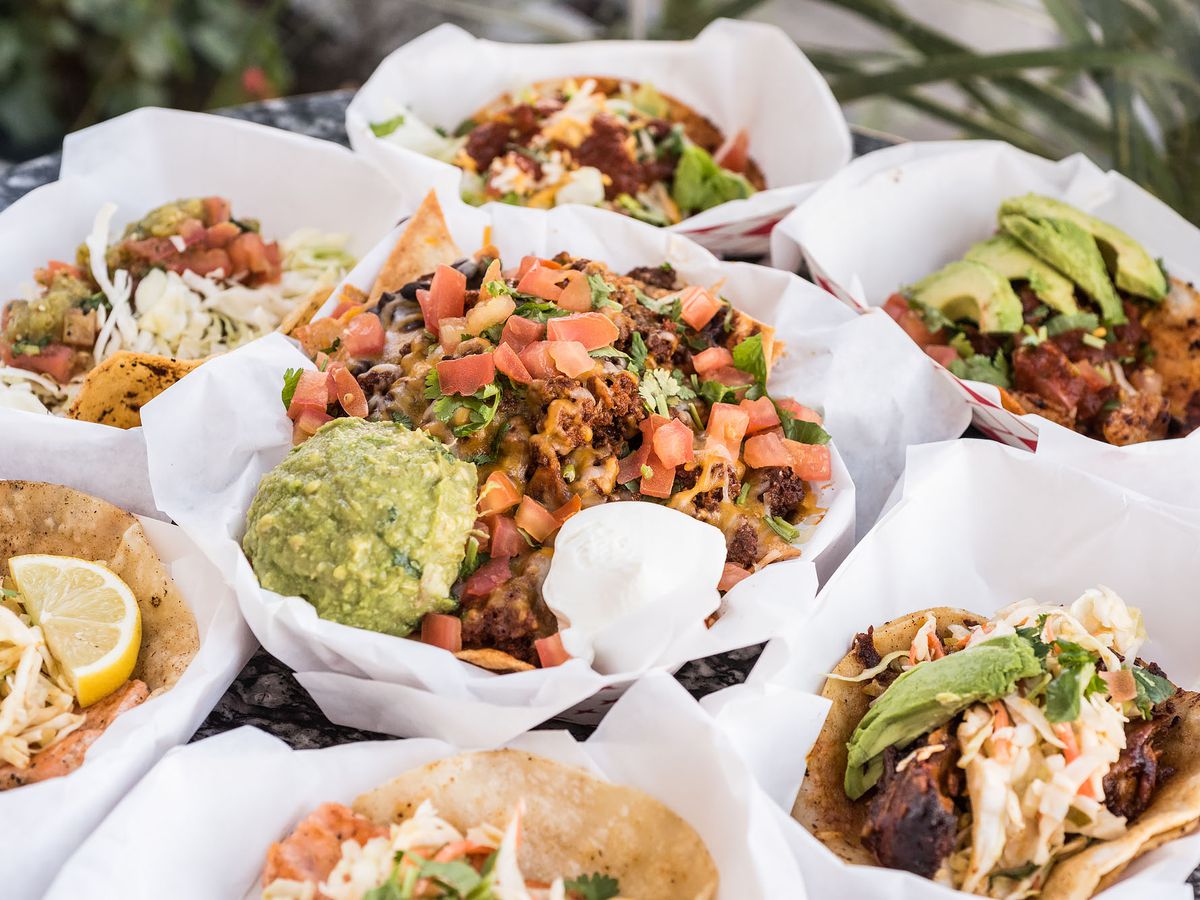 Sky’s Gourmet Tacos has a slate colored table that is filled with open-face tacos and bowls.