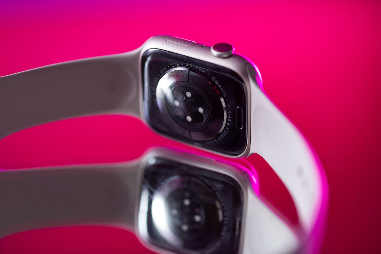 Sensor array of the Apple Watch Series 8 on a reflective pink surface.
