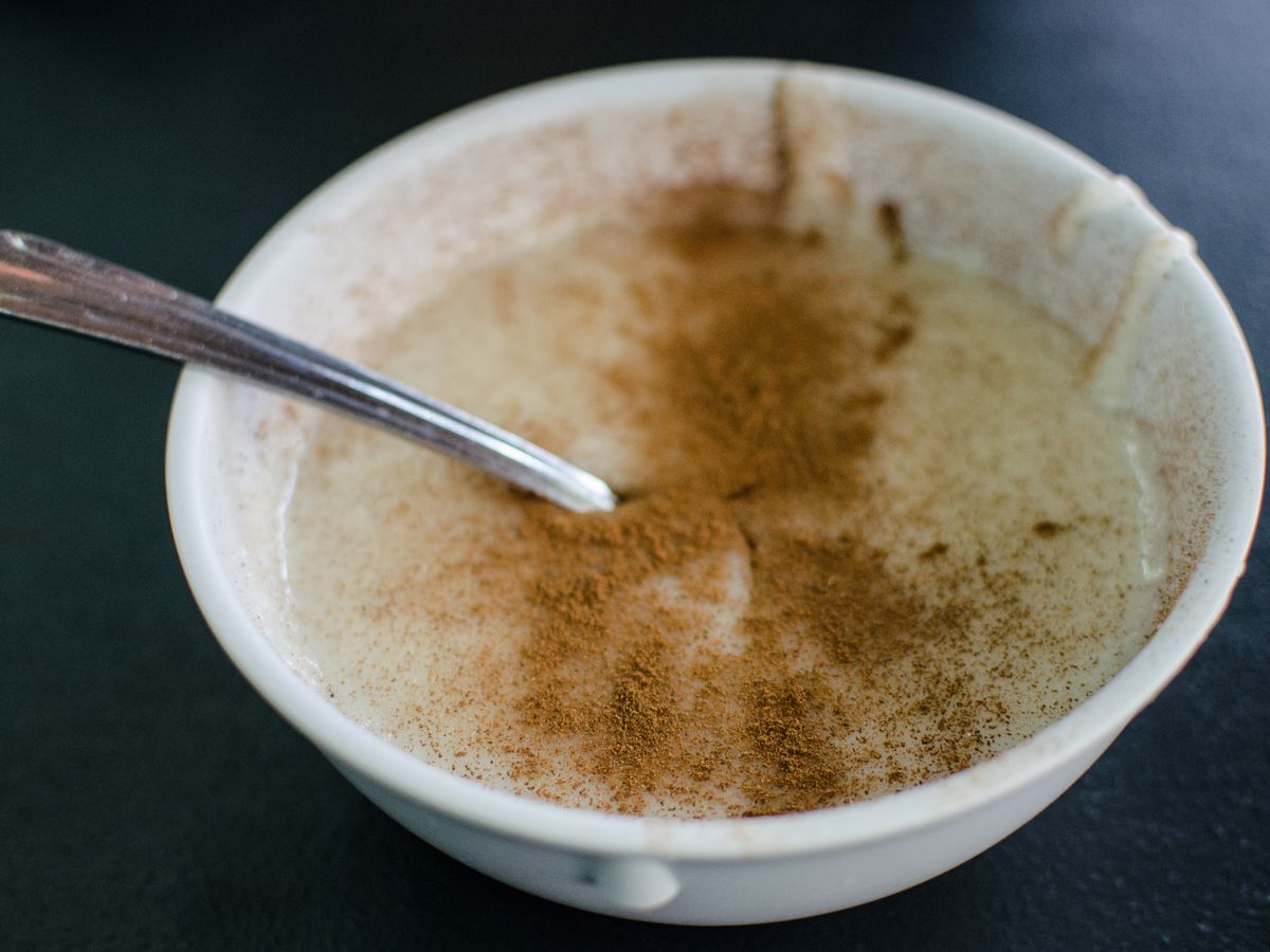 A white bowl of Cream of Wheat sits on a dark background, topped with a generous sprinkling of cinnamon