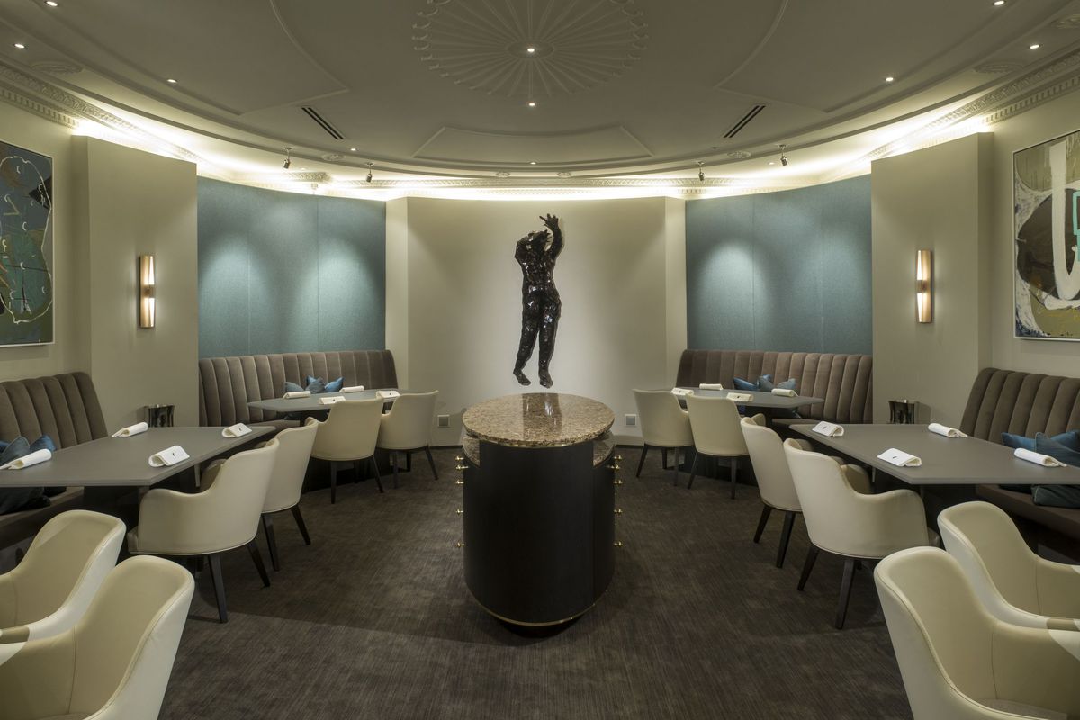 One of Alinea’s dining areas is modern with light off-whites and a central statue.