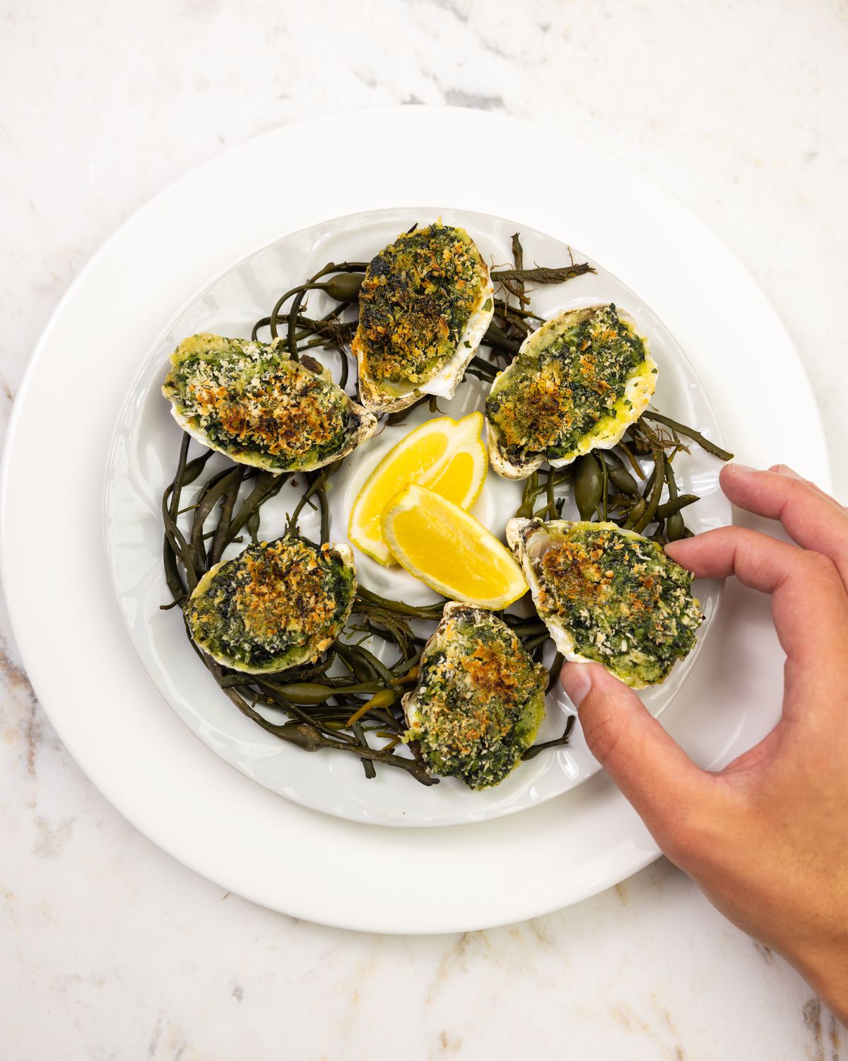A plate of oysters Rockefeller with lemon wedges at the center