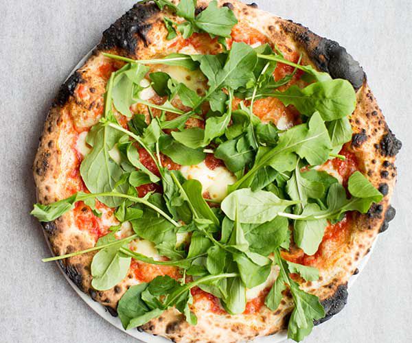 From above, a full pizza topped with spinach