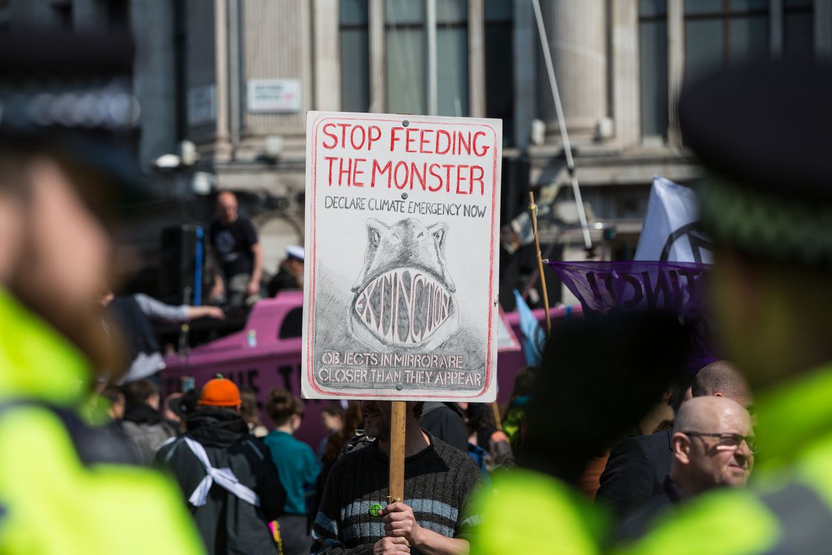 A man holds a placard with a dinosaur drawn on it at during a protest against climate change in the middle of Oxford Circus on 15th April, 2019 in London, United Kingdom. 