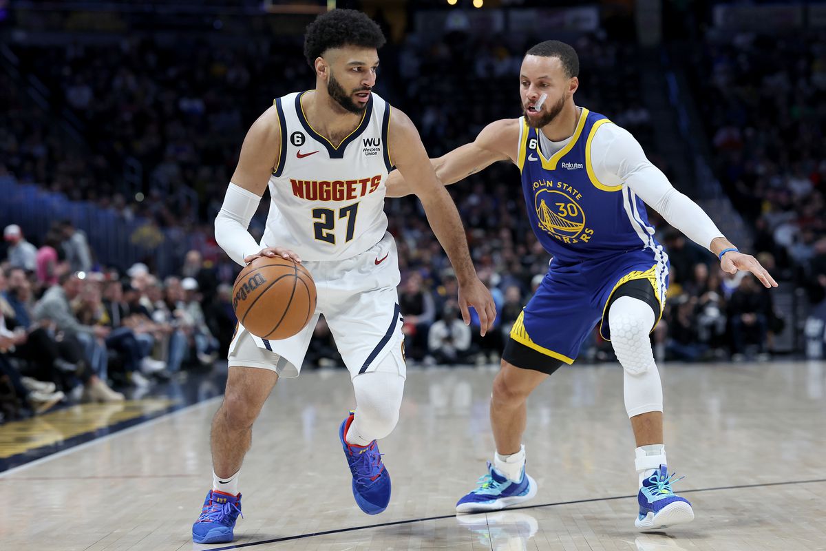 Steph Curry, with his mouthguard hanging out of his mouth, defending Jamal Murray 
