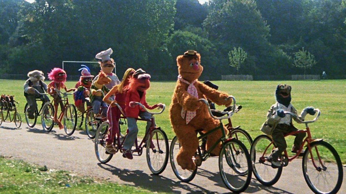 Muppets riding bicycles through the park.