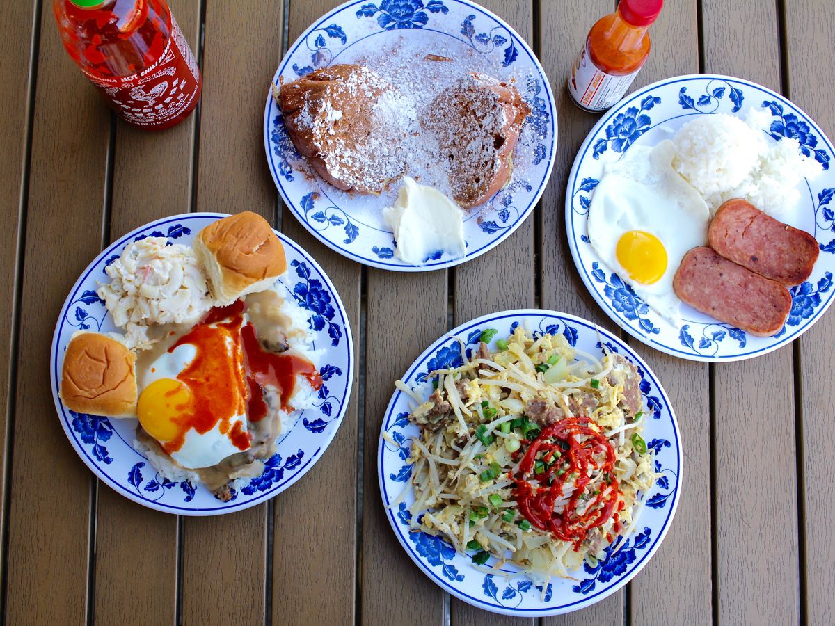 Colorful Hawaiian plates on a slatted table with sauces, eggs, spam and rice.