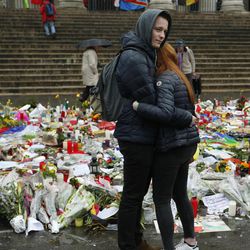 A couple embrace in front of tributes placed in a memorial for victims of the recent attacks on Brussels at the Place de la Bourse in Brussels, Friday, March, 25, 2016. Amid signs that life in Brussels was returning to some sort of normality on the third day of mourning the dead, authorities lowered Belgium's terror-threat level by one notch. However, they said the situation remained grave and another attack is "likely and possible." Belgium had been on its highest alert since Tuesday's bombings. 