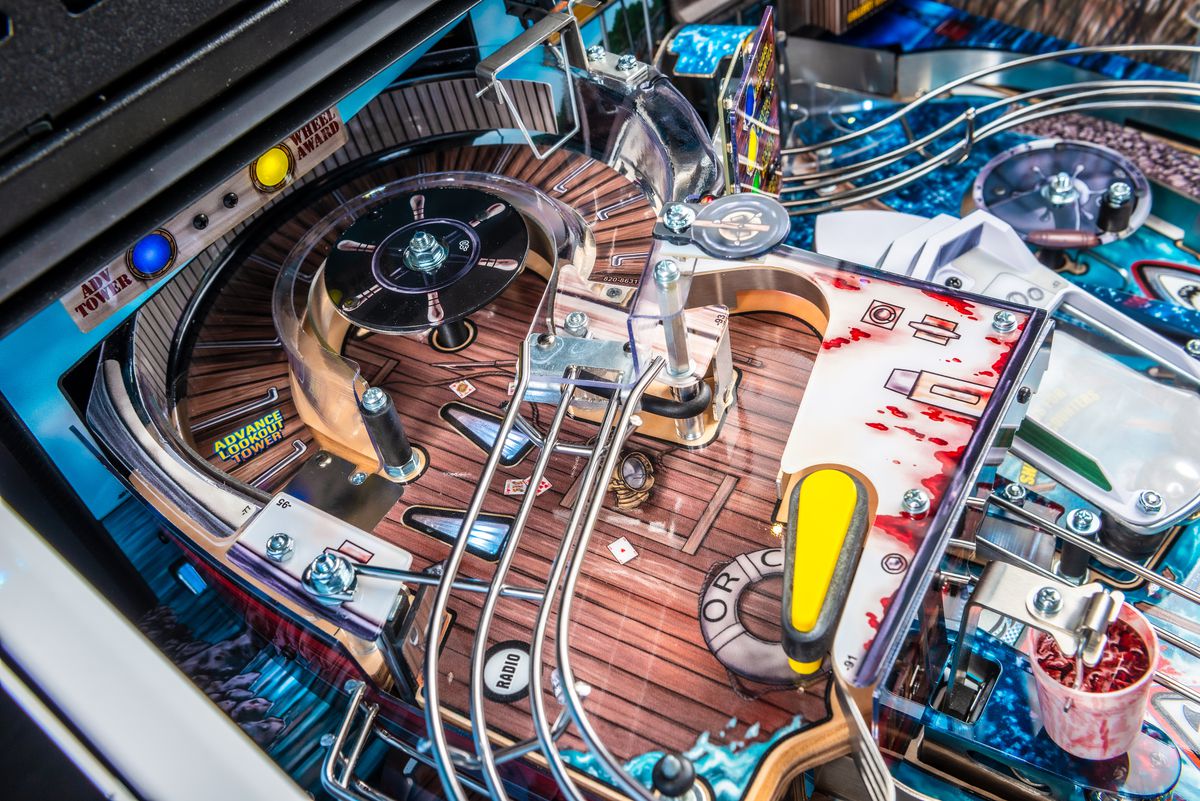 A close up photograph of the playfield of the pinball table Jaws, focused on the raised playing field that represents the Orca fishing boat and lookout tower