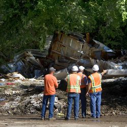 Geologists and other workers inspect where a home used to be where a landslide occured beneath a broken canal in The Island area of Logan on Sunday, July, 12, 2009.  