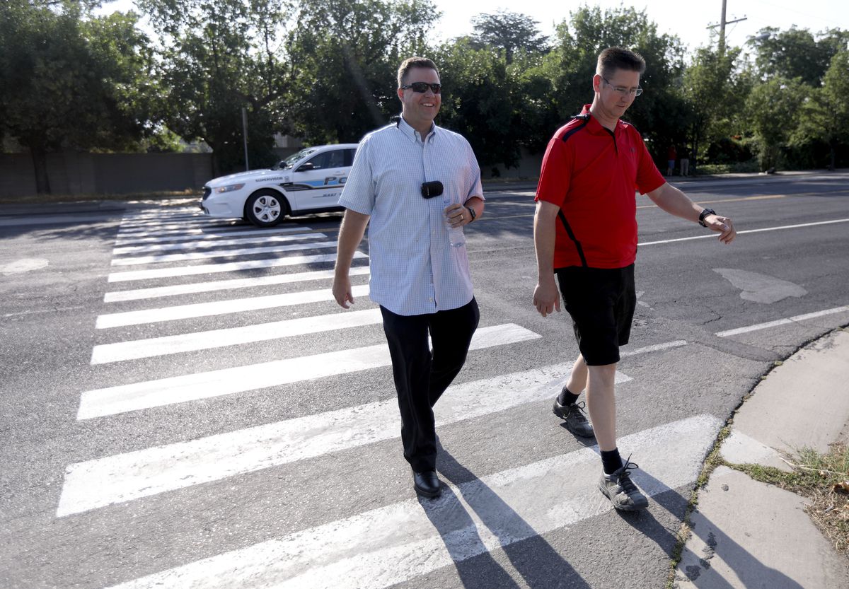 A West Valley police officer drives through a school zone crosswalk while two plainclothes detectives, Darren Mower and Thomas Sanford, are still crossing the street during a crosswalk safety operation in West Valley City on Tuesday, Aug. 7, 2018. Traffic