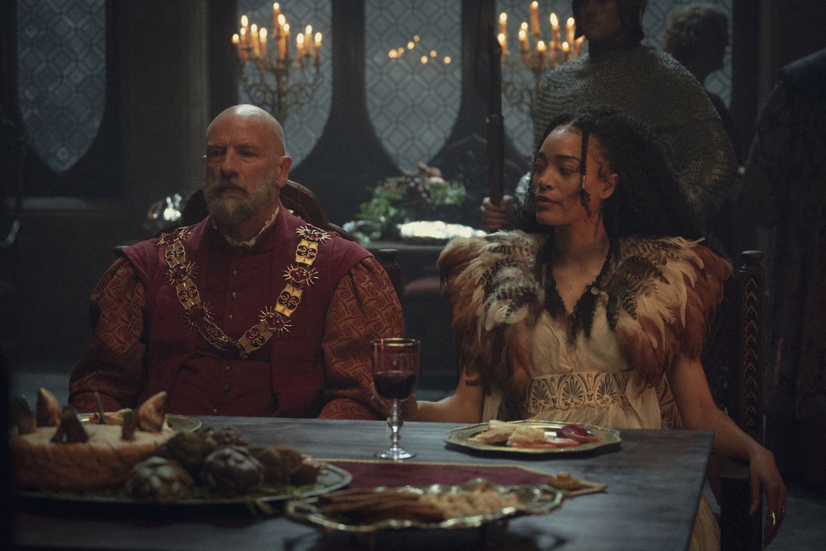 Dijkstra (Graham McTavish) and Philippa (Cassie Clare) sit together at a set dinner table in The Witcher.