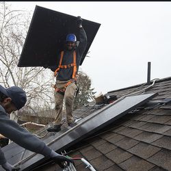 Justin Kourbelas, left, and Tyler Eichmeier, of Go Solar Energy, install solar panels on a house in Holladay on Friday, April 6, 2018.