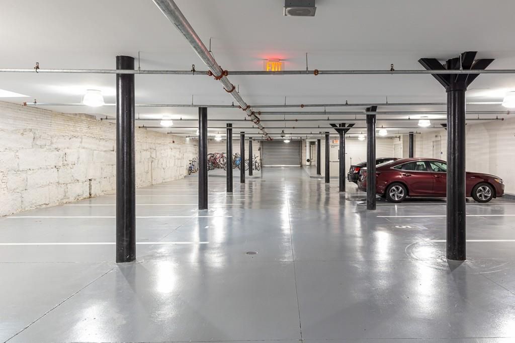 A low-ceilinged, clean-floored garage with cars parked in some of the spots. 