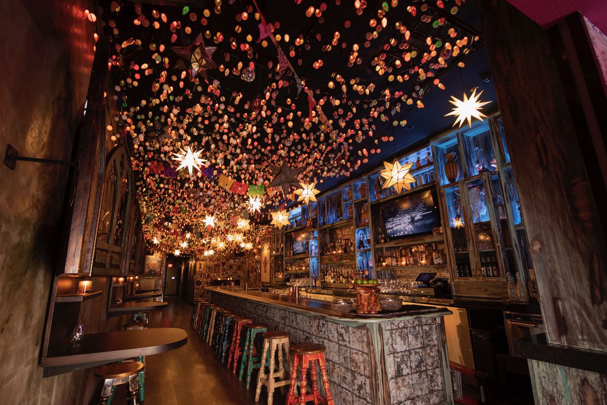 The inside of a bar with twinkle lights above and a bar on the right.