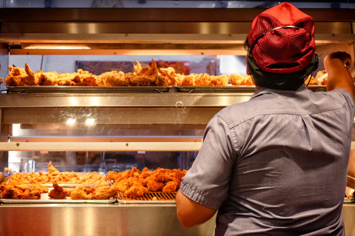 A worker at a fast-food fried chicken restaurant assembles an order.