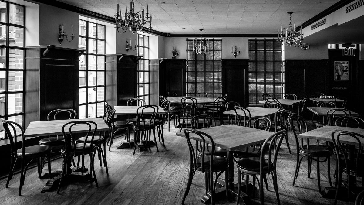 A black and white photo of an empty restaurants with empty tales and chairs placed next to each other