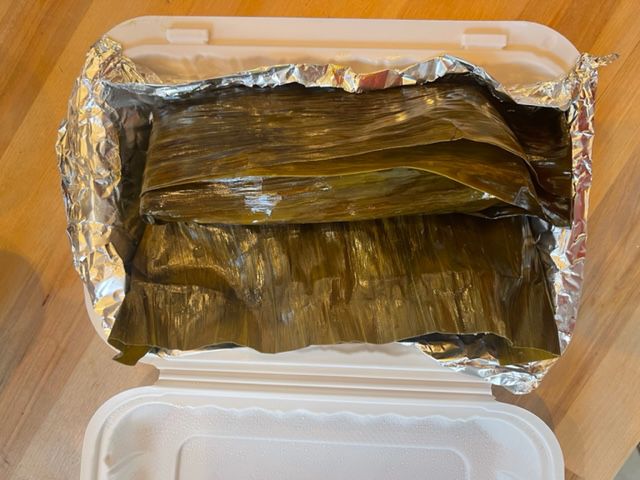 Two tamales in a takeout container. 