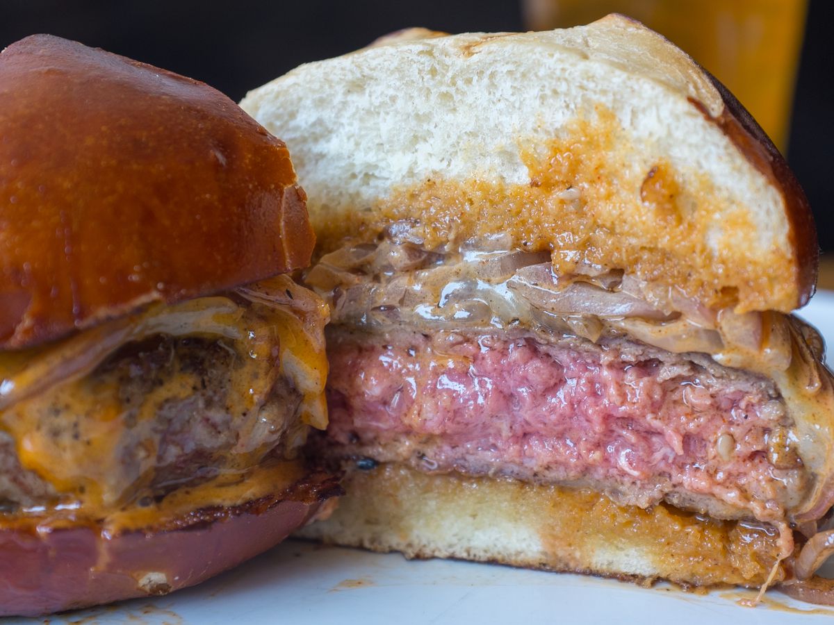 The cross-section of a dry-aged burger, blanketed in American and a handful of caramelized onions.