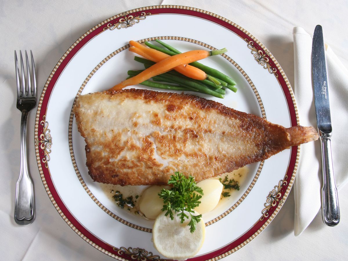 Fish on a white plate with silver utensils