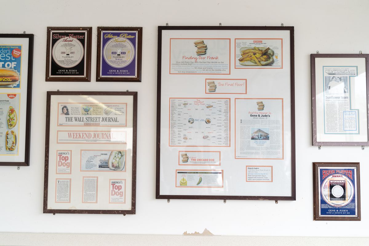 Framed articles and awards on a white wall.