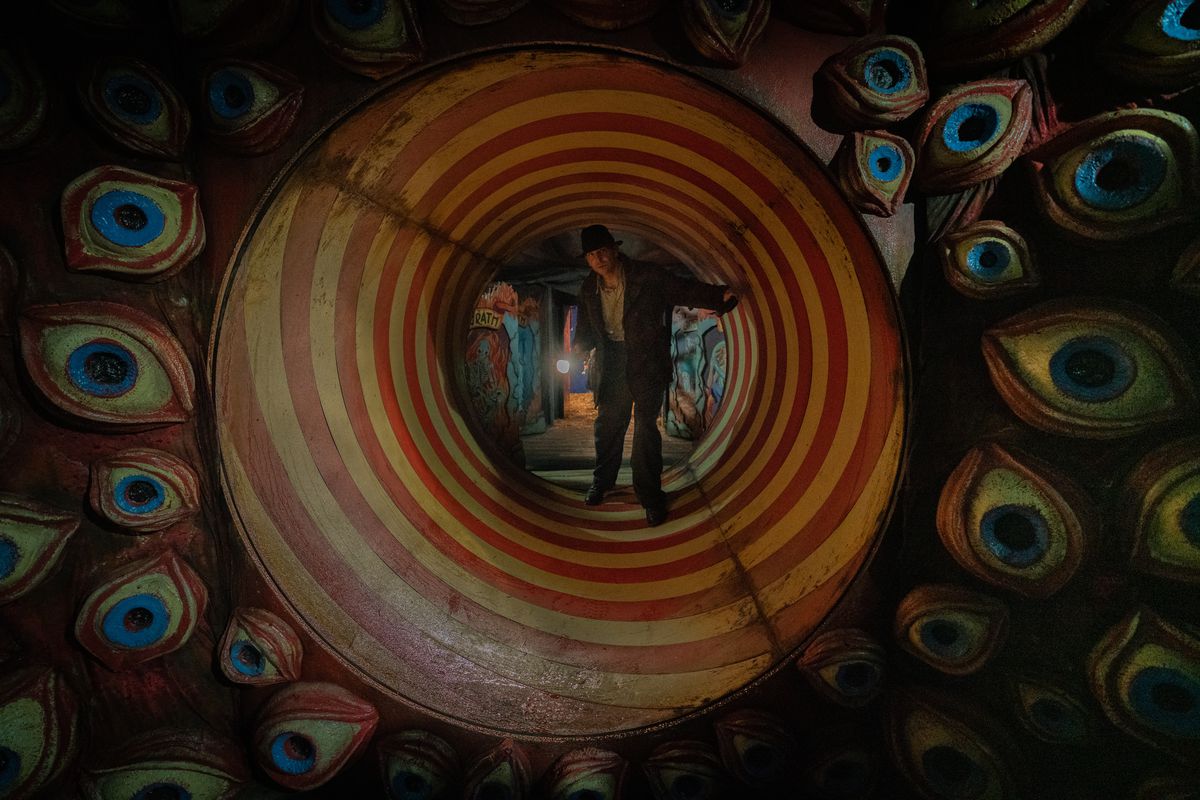 Bradley Cooper as Stan Carlisle in a funhouse tunnel surrounded by eyes in Guillermo del Toro’s Nightmare Alley.